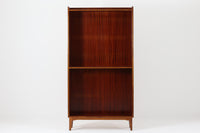 スウェーデンで製造されたヴィンテージのブックシェルフ。本体には深みのある美しいマホガニー材を使用し、縁や脚部にはナチュラルな風合いのビーチ材を組み合わせた、上品で洗練されたデザインが魅力です。特徴的なのは、上から下に向かって奥行が深くなる構造。視覚的な軽やかさを保ちながらも収納力を確保し、機能性とデザイン性を両立した作りになっています。脚部の緩やかな曲線が北欧家具らしいエレガントな印象を与え、インテリアに品のある温かみをプラスしてくれます。書籍やディスプレイアイテムを美しく収納できる、実用性とデザイン性を兼ね備えた一品。シンプルながらもこだわりを感じさせる北欧ヴィンテージ家具をお探しの方におすすめです。