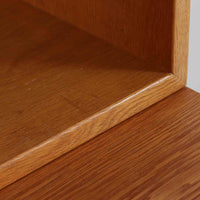 Borge Mogensenがデザインを手がけ、Karl Andersson社によって製造されたこちらのディスプレイシェルフは、チークとオークの異素材の美しいコントラストが際立つ北欧ビンテージ家具です。上段は可動式の棚板を備えたオープン収納、下段は左右に5杯ずつの引き出しを備え、収納力と機能性に優れた構成となっています。温かみのある木肌と丸型取手のアクセントが、空間に柔らかな印象を添えつつ、経年による風合いがヴィンテージらしい魅力を引き立てます。書斎やリビングでの書籍や雑貨の整理におすすめの一台です。