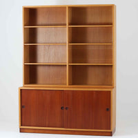 Borge Mogensenがデザインし、Karl Andersson社により製造されたこちらのディスプレイシェルフは、チーク材とオーク材のコントラストが美しいスウェーデン製の北欧ビンテージ家具です。上部はオープン構造で5段の棚が左右に配されており、書籍や器、小物のディスプレイに最適で、下部にはスライド扉収納も備え実用性にも優れています。幅135cmと存在感のあるサイズながら、直線的で端正な佇まいが空間に凛とした印象を与える一台です。