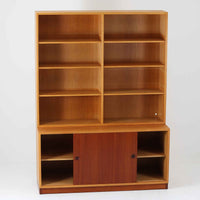 Borge Mogensenがデザインし、Karl Andersson社により製造されたこちらのディスプレイシェルフは、チーク材とオーク材のコントラストが美しいスウェーデン製の北欧ビンテージ家具です。上部はオープン構造で5段の棚が左右に配されており、書籍や器、小物のディスプレイに最適で、下部にはスライド扉収納も備え実用性にも優れています。幅135cmと存在感のあるサイズながら、直線的で端正な佇まいが空間に凛とした印象を与える一台です。
