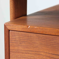 カイ・クリスチャンセンがデザインし、FM furniture社によって製造されたこちらの両袖デスクは、チーク材の美しい木目と温かみのある色合いが魅力の北欧ビンテージ家具です。左右には3杯ずつの引き出し、中央には扉付き収納を備え、背面にはオープンシェルフが設けられており、デスクとしての高い収納力と機能性を誇ります。壁付けはもちろん、間仕切りとしても活用できるため、空間の中心にも映える設計です。丸みを帯びた取手や脚部など、細部にまでこだわった意匠は、カイ・クリスチャンセンらしい洗練された美しさを体現しており、上質なワークスペースを演出します。