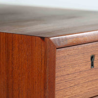 カイ・クリスチャンセンがデザインし、FM furniture社によって製造されたこちらの両袖デスクは、チーク材の美しい木目と温かみのある色合いが魅力の北欧ビンテージ家具です。左右には3杯ずつの引き出し、中央には扉付き収納を備え、背面にはオープンシェルフが設けられており、デスクとしての高い収納力と機能性を誇ります。壁付けはもちろん、間仕切りとしても活用できるため、空間の中心にも映える設計です。丸みを帯びた取手や脚部など、細部にまでこだわった意匠は、カイ・クリスチャンセンらしい洗練された美しさを体現しており、上質なワークスペースを演出します。