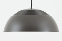アルネ・ヤコブセンによってデザインされ、Louis Poulsen(ルイスポールセン)より製造されたAJロイヤル ペンダントライト。こちらは希少なグラファイトグレーカラーで、落ち着いたトーンが空間にシックな雰囲気を演出します。直径50cmの大型サイズで、光源を遮る構造と放射状に配置されたルーバーにより、眩しさを抑えた柔らかい光が空間全体を包み込みます。点灯時には上部のスリットから漏れる光も美しく、デザイン性と機能性を兼ね備えた一品です。外観には小傷や使用感がありますが、ビンテージならではの風合いとしてお楽しみいただけます。