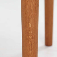 Hans J. WegnerがデザインしGetama社より製造されたGE80/86センターテーブルは、オーク無垢材を贅沢に使用した堅牢かつ端正な一台です。丸みを帯びた天板の縁や、すっきりとした円錐形の脚部が特徴で、シンプルでありながら温かみのある北欧デザインを体現しています。幅75cmと扱いやすいサイズ感で、リビングの中心に置いてコーヒーテーブルとしてはもちろん、サイドに添えても活躍する汎用性の高い家具です。経年による木肌の変化が深みを増し、ビンテージならではの存在感を放ちます。