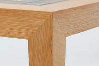 デンマークの家具デザイナー、Severin Hansen Jr.によってデザインされたビンテージのサイドテーブルです。製造はデンマークの名門家具メーカー「Haslev(ハスレヴ)」社。天板にはRoyal Copenhagen(ロイヤルコペンハーゲン)のアートタイルが贅沢にあしらわれています。タイルはNils Thorsson(ニルス・トーソン)が手掛けた人気の「BACA(バッカ)」シリーズ。象徴的なブルーとブラウンの色使いと、有機的かつ幾何学的なモチーフが印象的で、アートピースとしての存在感を放ちます。テーブル本体はオーク材を使用しており、Severin Hansen Jr.の特徴でもあるシャープなカットが施されたコーナーと、すっきりとしたテーパードレッグが、シンプルながら洗練された美しさを醸し出しています。ヴィンテージならではの深い味わいと、アート性・機能性を兼ね備えた一台。リビングやベッドサイドに、さりげなく上質な北欧デザインを取り入れてみてはいかがでしょうか。