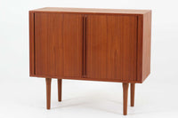デンマークのデザイナー、Kai Kristiansen(カイ・クリスチャンセン)によってデザインされた、Fm furniture社製のビンテージキャビネットです。素材には上質なチーク材が用いられており、深みのある美しい木目とあたたかみのある色合いが魅力です。フロントには、機能性とデザイン性を兼ね備えた蛇腹扉が採用されており、開閉の動作そのものが楽しめる一台です。内部にはフェルトが敷かれた引き出し2段と収納スペースがあり、カトラリーや書類、小物の整理にも最適です。高さのある丸脚は、北欧家具らしい軽やかな印象を与えながらも、根元にかけてややふくらみを持たせた独特のフォルムとなっており、全体のデザイン性を高めています。コンパクトなサイズ感は空間を圧迫せず、リビングや玄関、書斎など様々なシーンに馴染みます。北欧デザインの美しさと実用性を兼ね備えたキャビネットです。