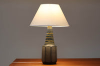 デンマーク・ボーンホルム島の名窯michael Andersen & Sonによるテーブルランプ。八角形のシャープなフォルムと、マットな質感の釉薬のコントラストが美しい一点です。落ち着いたブルーグレーのトーンがインテリアに静かなアクセントを添えてくれます。高さは約50cmとやや大きめで、程よい存在感があり、サイドボードやコンソールの上などにもおすすめです。シェードは新品のリネン製。