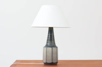 デンマーク・ボーンホルム島の名窯michael Andersen & Sonによるテーブルランプ。八角形のシャープなフォルムと、マットな質感の釉薬のコントラストが美しい一点です。落ち着いたブルーグレーのトーンがインテリアに静かなアクセントを添えてくれます。高さは約50cmとやや大きめで、程よい存在感があり、サイドボードやコンソールの上などにもおすすめです。シェードは新品のリネン製。
