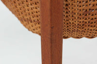 デンマークの名デザイナーSeverin Hansen Jr.が手掛け、Haslev社によって製造された北欧ビンテージのソーイングテーブルです。素材には温かみのあるチーク材が使用され、シャープな接合部とすっきりとしたテーパードレッグが洗練された佇まいを演出しています。特徴的な籐のバスケットは糸や道具類をたっぷりと収納でき、天板下のスライドトレイには仕切りがあり細かな道具の整理にも便利です。バスケットを支える木製レールの一部に欠けがありますが、使用には支障ありません。実用性と美しさを兼ね備えた一台で、裁縫道具の収納にはもちろん、サイドテーブルとしてもおすすめです。