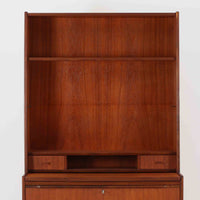 チーク材の温もりが魅力のこちらのディスプレイシェルフは、引き出し収納と棚が一体となった北欧ビンテージらしい実用性と美しさを兼ね備えた一台で、下段には鍵付きの3杯引き出し、上段には棚が3段設けられており、書斎やリビングの収納兼飾り棚としてはもちろん、店舗什器としても活躍します。細身の丸脚が全体に軽やかな印象を与え、チーク材特有の深みのある色合いと経年による艶が上質な雰囲気を醸し出しています。