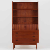 Johannes Sorth(ヨハネス・ソース)によるNexo Mobelfabrik社製のチーク材ディスプレイシェルフです。幅100cmと程よいサイズ感で、上段の棚は高さのある書籍やオブジェを飾るのに適しており、中央の蛇腹扉の内側には小引き出しや仕切りが備わり、細かな収納にも対応します。下段の3杯の引き出しは収納力に優れ、衣類や書類の整理に便利です。直線的なフォルムに温かみのあるチーク材の木目が映え、経年の艶が深みを増したビンテージらしい風合いを楽しめます。機能性と美観を兼ね備えた北欧家具の魅力が詰まった一台です。