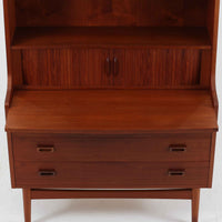 Johannes Sorth(ヨハネス・ソース)によるNexo Mobelfabrik社製のチーク材ディスプレイシェルフです。幅100cmと程よいサイズ感で、上段の棚は高さのある書籍やオブジェを飾るのに適しており、中央の蛇腹扉の内側には小引き出しや仕切りが備わり、細かな収納にも対応します。下段の3杯の引き出しは収納力に優れ、衣類や書類の整理に便利です。直線的なフォルムに温かみのあるチーク材の木目が映え、経年の艶が深みを増したビンテージらしい風合いを楽しめます。機能性と美観を兼ね備えた北欧家具の魅力が詰まった一台です。