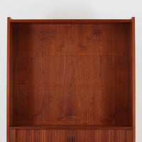 Johannes Sorth(ヨハネス・ソース)によるNexo Mobelfabrik社製のチーク材ディスプレイシェルフです。幅100cmと程よいサイズ感で、上段の棚は高さのある書籍やオブジェを飾るのに適しており、中央の蛇腹扉の内側には小引き出しや仕切りが備わり、細かな収納にも対応します。下段の3杯の引き出しは収納力に優れ、衣類や書類の整理に便利です。直線的なフォルムに温かみのあるチーク材の木目が映え、経年の艶が深みを増したビンテージらしい風合いを楽しめます。機能性と美観を兼ね備えた北欧家具の魅力が詰まった一台です。