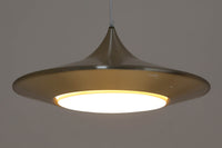 デンマークの照明メーカーLyfa社による、デザイナーEjnar B. mielby(アイナー・B・ミェルビー)が手がけた「Kuli(クーリ)」ペンダントライト。特徴的なホーン型のフォルムと、美しく仕上げられた真鍮カラーのシェードが印象的なビンテージ照明です。直径49cmと存在感のあるサイズ感で、ダイニングテーブルの上などにおすすめです。下面にはグリッド状のルーバーが備わっており、光源を柔らかく拡散しつつ眩しさを軽減する構造となっています。ソケット部分はE26口金、コードは引っ掛けシーリング仕様で、設置も簡単です。経年に伴う小傷や塗装剥がれが一部見られますが、全体としてはビンテージらしい雰囲気を保っています。空間にミッドセンチュリーのエッセンスを加える一品としておすすめです。