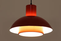 Fog & Morup(フォグ&モーラップ)社より、Jo Hammerborg(ヨー・ハーマボー)によってデザインされた「Lakaj」ペンダントライトです。直径34cmのシェードは、赤の外装と内側のホワイト&ボトムカバーの淡いイエローの配色が美しい光を柔らかく拡散し、空間に温もりと視覚的なアクセントを与えます。点灯時にはシェード上部から漏れる光が間接照明としても機能し、北欧ビンテージ家具と調和する洗練された雰囲気を演出します。ダイニングやリビングの照明に最適な、希少性と機能美を兼ね備えた一灯です。