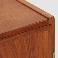 デンマーク製の収納キャビネットです。上段には観音開きの扉内に可動棚が設けられており、食器や書類をすっきりと整理できます。内部まで丁寧に仕上げられており、扉を開けてお気に入りの器やオブジェを飾る“見せる収納”としても楽しめます。扉には鍵が付属しており、大切なものを安全に保管することも可能です。下段には2杯の引き出しが備わり、小物類や日用品の収納にも便利。チーク材の豊かな木目と深みのある色合いが美しく、北欧家具らしい温もりを感じさせます。脚部のテーパー形状が全体を軽やかに見せ、シンプルながら上質な存在感を放つ一台です。