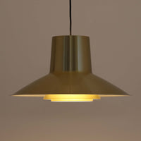 Svend Middelboeがデザインし、Nordisk Solar社より発表されたペンダントライト「Auditorie」です。直径49cmの大ぶりなサイズと、アルミ素材に施された美しい真鍮色の仕上げが特徴で、点灯時には下方向に効率よく光を届けつつ、柔らかく反射する光が空間を上品に彩ります。大胆なフォルムながらもバランスの取れたデザインは、1960年代北欧モダンのエッセンスを凝縮しており、ダイニングやリビングの主照明として存在感を放ちます。経年により深みを増した表情はビンテージならではの魅力で、機能性と美しさを兼ね備えた希少な一灯です。