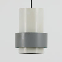 Jo HammerborgがFog & Morup社のためにデザインした「Central」ペンダントライトです。直径23cmのコンパクトなサイズながら、スチール製の二重シリンダー構造が特徴的で、点灯時には上下から光が広がり独特の陰影を演出します。外側のグレーと内側のホワイトがコントラストを生み、点灯時にはほのかなグリーンの光が漏れ出す美しいデザインです。ダイニングや小スペースに適したサイズで、北欧モダンのエッセンスを感じさせるビンテージ照明です。シェードの内側に施されたグリーンの塗装が、点灯時に柔らかなニュアンスを加え、空間に独特の雰囲気を演出します。