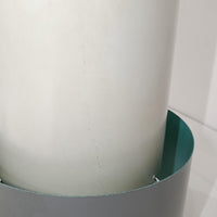 Jo HammerborgがFog & Morup社のためにデザインした「Central」ペンダントライトです。直径23cmのコンパクトなサイズながら、スチール製の二重シリンダー構造が特徴的で、点灯時には上下から光が広がり独特の陰影を演出します。外側のグレーと内側のホワイトがコントラストを生み、点灯時にはほのかなグリーンの光が漏れ出す美しいデザインです。ダイニングや小スペースに適したサイズで、北欧モダンのエッセンスを感じさせるビンテージ照明です。シェードの内側に施されたグリーンの塗装が、点灯時に柔らかなニュアンスを加え、空間に独特の雰囲気を演出します。