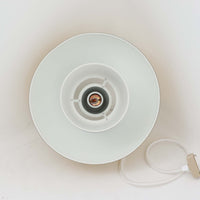 Louis Poulsen社製の小ぶりなペンダントライト「Doo-Wop」です。直径29cmの扱いやすいサイズで、真鍮カラーの上部シェードとホワイトの内側シェードのコントラストが美しいデザイン。点灯時には上下に光を広げ、空間を柔らかく照らし出します。1950年代にデンマーク海軍と共同で開発されたモデルで、シンプルながらも存在感のある佇まいが魅力です。ダイニングやキッチンに適しており、ビンテージならではの味わい深い風合いをお楽しみいただけます。さらに、現行品とは異なりシェードはマイナスネジで固定されており、当時のオリジナルならではのディテールが残されています。