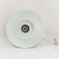 Louis Poulsen社製の小ぶりなペンダントライト「Doo-Wop」です。直径29cmの扱いやすいサイズで、真鍮カラーの上部シェードとホワイトの内側シェードのコントラストが美しいデザイン。点灯時には上下に光を広げ、空間を柔らかく照らし出します。1950年代にデンマーク海軍と共同で開発されたモデルで、シンプルながらも存在感のある佇まいが魅力です。ダイニングやキッチンに適しており、ビンテージならではの味わい深い風合いをお楽しみいただけます。さらに、現行品とは異なりシェードはマイナスネジで固定されており、当時のオリジナルならではのディテールが残されています。