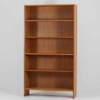 Hans J. Wegner(ハンス・J・ウェグナー)によるデザインで、Ry Mobler社から発表されたブックシェルフ「RY8」です。オーク材を用いたナチュラルな風合いと端正なラインが美しく、ウェグナーらしい機能美を感じさせます。通常モデルでは1枚が固定棚で他は可動棚となっていますが、本品は全ての棚板が取り外し可能な希少タイプで、用途に応じて高さを自在に調整できます。背面には製造年月のスタンプが残り、当時のクラフトマンシップを今に伝えています。書籍収納はもちろん、リビングやオフィスのディスプレイシェルフとしても活躍する一台です。