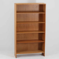 Hans J. Wegner(ハンス・J・ウェグナー)によるデザインで、Ry Mobler社から発表されたブックシェルフ「RY8」です。オーク材を用いたナチュラルな風合いと端正なラインが美しく、ウェグナーらしい機能美を感じさせます。通常モデルでは1枚が固定棚で他は可動棚となっていますが、本品は全ての棚板が取り外し可能な希少タイプで、用途に応じて高さを自在に調整できます。背面には製造年月のスタンプが残り、当時のクラフトマンシップを今に伝えています。書籍収納はもちろん、リビングやオフィスのディスプレイシェルフとしても活躍する一台です。