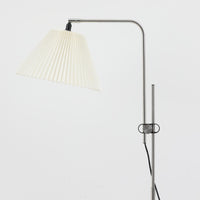 Michael Bang(マイケル・バン)によるデザインで、Le Klint(レ・クリント)から発表されたフロアランプModel 321です。高さ131cmのスチール製フレームは、無駄のない直線的なフォルムと精巧なディテールが際立ち、モダンな空間に調和します。特徴的なスライド機構によりランプの高さを調整でき、読書灯から間接照明まで幅広い用途に対応。ハンドクラフトによるプリーツシェードは柔らかい光を生み出し、北欧ビンテージならではの温もりと機能美を感じさせます。