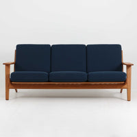 Hans J. Wegner(ハンス・J・ウェグナー)によるデザインで、Getama社から発表されたトリプルソファ「GE290」です。堅牢なオーク材フレームにボリュームのあるクッションを組み合わせた構造で、しっかりとした座り心地と安定感を実現しています。ビンテージならではのクッション内部にはスプリングが内包されており、しなやかな弾力と快適な座り心地を長く保ちます。特徴的なアームのラインや背面の格子フレームは、どの角度から見ても美しく、空間の主役となる存在感を放ちます。ブルー系ファブリックがオーク材の温もりと調和し、北欧らしい落ち着いた雰囲気を演出する名作ビンテージソファです。