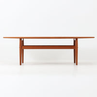 Grete Jalkがデザインし、Glostrup Mobelfabrikで製作されたこちらのセンターテーブルは、端正なプロポーションと軽やかな構造が魅力の北欧ビンテージ品です。幅160cmのゆとりある天板下にはスラット状の棚板を備え、雑誌やブランケットなどを整理しながら使える実用性も兼ね備えています。丸みを帯びた脚部や天板縁の丁寧な仕上げからは、女性デザイナーらしい繊細な美意識と当時の高い木工技術が感じられ、経年により深みを増した木肌が空間に落ち着いた存在感をもたらします。