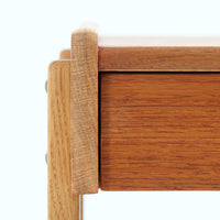 AB Carlstrom&CO Mobelfabrik社製のサイドチェストは、チーク材とオーク材を組み合わせた北欧ビンテージ家具です。温かみのあるチークの引き出し前板と、明るいオークのフレームが美しいコントラストを生み出し、軽やかで洗練された印象を与えます。上段には小物収納に便利な引き出し、下段にはオープンシェルフを備え、実用性とデザイン性を両立。幅46cmとコンパクトなサイズ感は、ベッドサイドやソファ横でのサイドテーブルとしても最適で、限られたスペースにも収まりやすい設計です。シンプルながら素材の質感と北欧家具ならではの職人技が息づく一台で、空間に温もりと個性を添えてくれます。