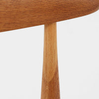 Hans J. Wegnerがデザインし、Fritz Hansen社より発表されたFH4103チェアは、三角形に近い座面と滑らかな曲線を描く笠木が特徴の北欧ビンテージ家具です。フレームには堅牢なオーク材、座面には温かみあるチーク材を組み合わせ、素材のコントラストが美しいバランスを生み出しています。彫刻的なフォルムながら軽やかで実用的な構造は、ダイニングチェアとしてはもちろん、空間のアクセントピースとしても存在感を放ちます。経年による木肌の深い風合いが、ビンテージならではの魅力を引き立てています。
