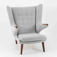 Hans J. Wegnerによってデザインされ、AP Stolen社より製造された名作AP-19、通称「ベアチェア」は、その名の通り熊が抱きかかえるような形状のアームが特徴のシングルソファです。張りぐるみのシートを支えるチーク材の脚部は、繊細さと力強さを兼ね備えた見事な造形で、ウェグナーらしい有機的なフォルムと高い快適性が融合した一台です。張地にはグレー系のファブリックを使用し、空間に馴染みやすい落ち着いた印象に仕上げられています。名作ゆえに現存数も限られ、ビンテージ市場でも高い評価を受ける希少な逸品です。