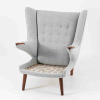 Hans J. Wegnerによってデザインされ、AP Stolen社より製造された名作AP-19、通称「ベアチェア」は、その名の通り熊が抱きかかえるような形状のアームが特徴のシングルソファです。張りぐるみのシートを支えるチーク材の脚部は、繊細さと力強さを兼ね備えた見事な造形で、ウェグナーらしい有機的なフォルムと高い快適性が融合した一台です。張地にはグレー系のファブリックを使用し、空間に馴染みやすい落ち着いた印象に仕上げられています。名作ゆえに現存数も限られ、ビンテージ市場でも高い評価を受ける希少な逸品です。