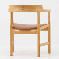 Hans J. Wegnerが1975年にデザインし、PP Mobler社が製造したPP52 Captain's Chairは、背からアームまで滑らかにつながる一体成型の美しいフォルムが魅力のアームチェアです。素材には木目の美しいアッシュ材と本革が用いられ、背面には象徴的な埋木の意匠が施されています。座面はゆったりとしたカーブで快適な座り心地を実現し、ダイニングからデスクシーンまで幅広く対応します。現在も製造されており、現行品の販売価格は約90~100万円程度となっています。