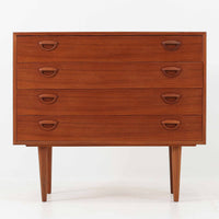 カイ・クリスチャンセンが手掛け、フェルドバレス・モーベルファブリック社によって製作された4段チェストは、北欧ビンテージらしい端正な佇まいと高い実用性を兼ね備えた一台です。良質なチーク材を用いた本体は、木目の美しさが前面に表れ、半円状に削り出された取手や細身のテーパードレッグが、全体に軽やかで洗練された印象を与えています。引き出しは深さにゆとりがあり収納力も十分で、衣類や小物の整理に最適です。経年変化によって深みを増したチークの色合いが空間に温もりを添え、リビングや寝室、書斎など幅広いシーンで主役として活躍します。