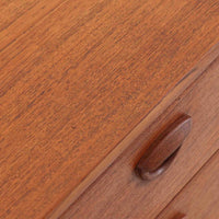 カイ・クリスチャンセンが手掛け、フェルドバレス・モーベルファブリック社によって製作された4段チェストは、北欧ビンテージらしい端正な佇まいと高い実用性を兼ね備えた一台です。良質なチーク材を用いた本体は、木目の美しさが前面に表れ、半円状に削り出された取手や細身のテーパードレッグが、全体に軽やかで洗練された印象を与えています。引き出しは深さにゆとりがあり収納力も十分で、衣類や小物の整理に最適です。経年変化によって深みを増したチークの色合いが空間に温もりを添え、リビングや寝室、書斎など幅広いシーンで主役として活躍します。