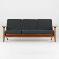 Hans J. Wegnerがデザインし、Getamaより製造された名作ソファ「GE290」です。オーク材の美しい木目を活かした堅牢なフレームと、背面まで美しく仕上げられたスポーク構造が特徴で、空間の中央にも映える洗練された佇まいを備えています。ゆったりとした3人掛けの座面は快適な掛け心地を実現し、リビングの主役として長く愛用できる一台。時代を超えて評価されるウェグナーならではの機能美と、ビンテージならではの味わい深い経年変化を存分に楽しめる北欧家具です。
