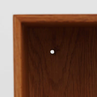 デンマークの建築家Mogens Koch(モーエンス・コッホ)によってデザインされ、名工房Rud. Rasmussen社で製造されたオーク無垢材のブックシェルフです。無駄のない端正なフォルムと精緻な組継ぎ構造が特徴で、堅牢さと美しさを兼ね備えています。ナチュラルなオークの木肌は経年により温かみを増し、シンプルながらも存在感のある佇まいを演出。縦横いずれの向きでも使用でき、複数を組み合わせて自由にレイアウトできる汎用性の高い北欧ビンテージ家具です。