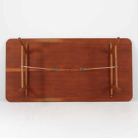 Borge Mogensenがデザインし、Soborg Mobler社より製造されたダイニングテーブル「BM1160」ハンティングテーブルです。現行品はカール・ハンセン社からも展開されていますが、こちらはSoborg社製造によるビンテージ品で、現在では入手が難しいチーク材仕様となっています。幅180cmと現行品よりややコンパクトなサイズ感で、日本の住空間にも取り入れやすい設計です。豊かな木目を持つチーク材の天板に、脚部を支える真鍮製クロスバーを組み合わせることで、堅牢さと美しさを兼ね備えています。角には滑らかな曲線が施され、温かみのある印象を添えつつ、家族や来客を迎える食卓として十分な広さを誇ります。真鍮パーツは構造的強度を高めると同時にビンテージらしい上質なアクセントとなり、シンプルでありながら存在感ある佇まいを演出。北欧家具ならではの実用性とデザイン性が息づき、年月を重ねることでさらに素材の風合いが深まり、空間を豊かに彩ります。