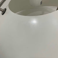 Pandul(パンドゥル)社が正規製造している、ハンス・J・ウェグナー(Hans J. Wegner)デザインのペンダントライト「JH604」です。1960年代にLouis Poulsen(ルイスポールセン)社で製造されていたモデルで、ウェグナーが自邸のためにデザインしたことでも知られています。直径50cmの存在感あるフォルムと、アルミ製シェードとステンレス製アームによる軽やかで堅牢な構造は、北欧デザインらしい機能美を体現。点灯時には下方向だけでなくシェード上部の隙間からも光が柔らかく漏れ、空間に奥行きを与えます。Pandulは1982年にデンマークで設立され、Louis Poulsenから受け継いだ名作を当時のデザインと品質を尊重して製造しているブランドです。なお、本品はプラスチック製コードリールが欠品しておりますが、全体として良好なコンディションを保っています。ヴィンテージデザインの魅力と現行製造ならではの安心感を兼ね備えた、北欧デザインを象徴する一灯です。