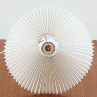 Esben KlintがLe Klintのためにデザインした「Model 311」テーブルランプです。高さ48cmの程よいサイズ感で、ガラスベースと真鍮パーツの組み合わせが美しい一品で、ベース部分はオリジナルです。シェードは後年に交換されたもので、LE KLINT社製のオリジナルではございませんが、同様にプラスチックシートを用いて製作されており、雰囲気を損なうことなく調和しています。点灯時には柔らかな光が広がり、落ち着いた雰囲気を演出。シンプルながらも存在感のあるデザインは、リビングやベッドサイドのアクセントとして最適です。デンマークデザインの伝統と職人技が息づくビンテージ照明です。