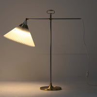 Esben Klintによるデザインで、Le Klint(レ・クリント)より発表されたテーブルランプModel 319です。真鍮とスチールを組み合わせた構造は、堅牢さと洗練された印象を兼ね備え、ハンドメイドのプリーツシェードが柔らかい光を拡散します。高さ75cmの程よいサイズ感とクロスバー構造による可動性が特徴で、デスクやリビングでの読書灯としても実用的です。経年による真鍮の風合いがビンテージらしい魅力を引き立て、空間にクラシカルで上質な雰囲気をもたらします。