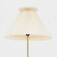 Aage Petersenによるデザインで、Le Klint社より発表されたモデル352のテーブルランプです。高さ62~85cmの昇降機能を備え、使用シーンに合わせて調整可能なのが魅力です。黒塗装のスチール支柱に真鍮パーツがアクセントとなり、プリーツ加工が美しい紙製シェードからは柔らかな光が広がります。特に点灯時にはシェードを透過して漏れる灯りが印象的で、空間を上品に演出します。現在は廃盤となっており、ビンテージ品のみ入手可能なモデルです。