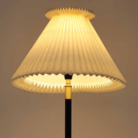 Aage Petersenによるデザインで、Le Klint社より発表されたモデル352のテーブルランプです。高さ62~85cmの昇降機能を備え、使用シーンに合わせて調整可能なのが魅力です。黒塗装のスチール支柱に真鍮パーツがアクセントとなり、プリーツ加工が美しい紙製シェードからは柔らかな光が広がります。特に点灯時にはシェードを透過して漏れる灯りが印象的で、空間を上品に演出します。現在は廃盤となっており、ビンテージ品のみ入手可能なモデルです。