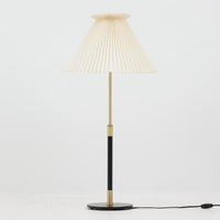 Aage Petersenによるデザインで、Le Klint社より発表されたモデル352のテーブルランプです。高さ62~85cmの昇降機能を備え、使用シーンに合わせて調整可能なのが魅力です。黒塗装のスチール支柱に真鍮パーツがアクセントとなり、プリーツ加工が美しい紙製シェードからは柔らかな光が広がります。特に点灯時にはシェードを透過して漏れる灯りが印象的で、空間を上品に演出します。現在は廃盤となっており、ビンテージ品のみ入手可能なモデルです。