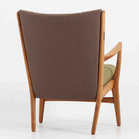 Hans J. Wegner(ハンス・J・ウェグナー)によるイージーチェア「AP16」。デンマークの名門AP stolen社より製造された一脚です。緩やかに傾斜した背もたれと、滑らかに削り出されたアームの曲線が美しく調和し、オーク材の力強い木目と職人技が際立ちます。背面にはブラウン、座面にはグリーンストライプの張地を採用し、上品ながらも温かみのある印象を与えます。現地デンマークのオークションで入手した確かな出自を持つ本品は、読書やくつろぎの時間をより豊かなものにしてくれます。経年による木部の風合いがさらに深みを加えています。