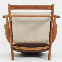 Hans J. Wegner(ハンス・J・ウェグナー)によるイージーチェア「AP16」。デンマークの名門AP stolen社より製造された一脚です。緩やかに傾斜した背もたれと、滑らかに削り出されたアームの曲線が美しく調和し、オーク材の力強い木目と職人技が際立ちます。背面にはブラウン、座面にはグリーンストライプの張地を採用し、上品ながらも温かみのある印象を与えます。現地デンマークのオークションで入手した確かな出自を持つ本品は、読書やくつろぎの時間をより豊かなものにしてくれます。経年による木部の風合いがさらに深みを加えています。