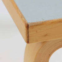 Alvar AaltoがデザインしArtek社より製造されたこちらのダイニングテーブルは、天板に落ち着いたグレートーンのリノリウム、脚部に美しい木肌のバーチ材を用いた北欧モダンデザインの名作で、L字型に曲げられた脚部がアアルトらしい柔らかな造形美を感じさせます。幅120cmの使い勝手のよいサイズ感で、ダイニングやワークスペースにもしっくりと馴染み、天板裏面には脚の付け替え跡が見られ、アアルト製品が多く採用されていたデンマークの公共施設で丁寧に使用されていた個体です。機能美と素材感のバランスに優れた一台です。