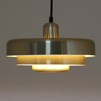Vitrika社製のペンダントライト「Gogo」です。直径30cmのサイズで、アルミ素材のシェードを段階的に重ねたデザインが特徴的です。光源を巧みに覆い隠しながらも、上下に柔らかく光を広げる構造により、落ち着いた雰囲気を演出します。真鍮のようなゴールド調の質感が高級感を加え、ビンテージならではの風合いと存在感を楽しめます。コンパクトながらも印象的なデザインで、ダイニングや玄関、書斎など多様なシーンに適した照明です。